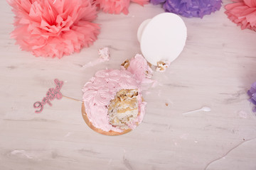 Photo zone with paper garlands, balloons, paper balls, pom poms, confetti and cream cake. Birthday cake. Smash cake. One year. Pink, white, violet, rose colors