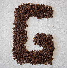 Image of roasted coffee beans shaped alphabet on a white background