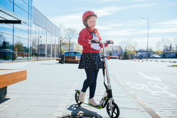 Beautiful red hair curly girl in helmet driving scooter outdoor on road outdoor in street with...