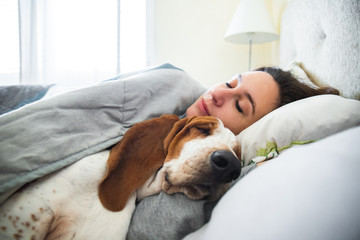 Girl and dog sleeping together comfortably and cuddled in bed in the morning. In bed with best...