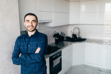 Portrait of confident young man standing by kitchen counter at home
