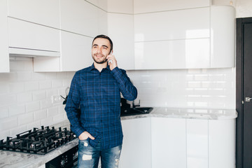 Young handsome Man talking on phone in kitchen at home