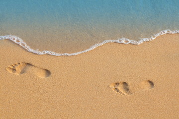 Texture background Footprints of human feet on the sand near the water on the beach © Kozlik_mozlik