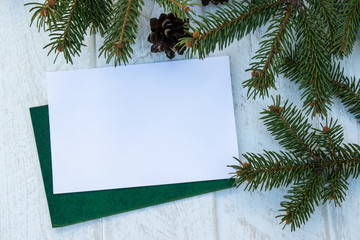 Green branches of a Christmas tree and cones on a white board background. Top view with copy space