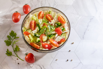 Salad with cucumbers, tomatoes, cabbage and greens, in a bowl on a white background. Horizontal orientation