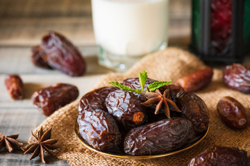 Ramadan food and drinks concept. Ramadan Lantern with Milk, dates fruit and green Mint leaves in a bowl on wooden table background.