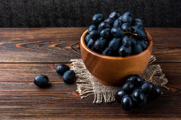 Blue grapes on dark wooden background. 