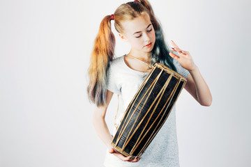 Young musician with indian drum. Beautiful girl playing the ethnic drums on gray background. Music...