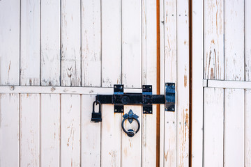 Backgrounds and textures: old white wooden door, closed with traditional forged metal lock