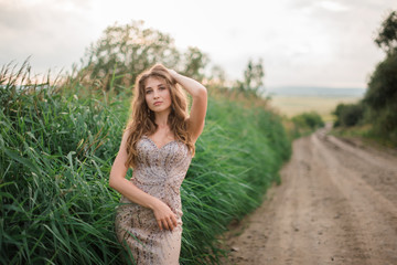 beautiful young girl in a summer dress in a field on a background of green grass