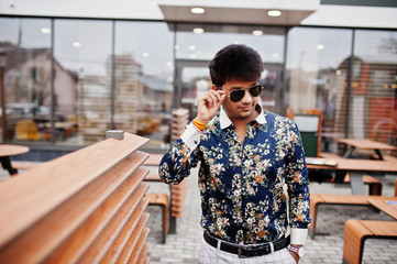Attractive and handsome stylish indian man wear on shirt and sunglasses standing in the terrace of modern lounge cafe at his work break.