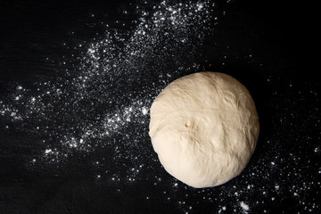 Raw dough for bread or pizza on a black background