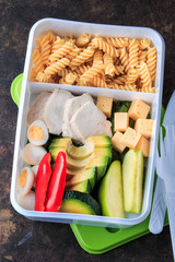 Healthy balanced lunch box. Noodles, avocado, cucumber, chicken and eggs. Bento Box Food. Cold school lunch box.