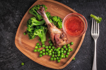 Portion of roast duck leg with green vegetables. Roast Duck with Vegetables on a bamboo plate.