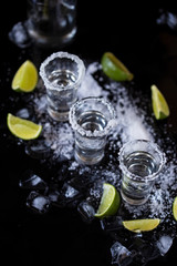 Fototapeta na wymiar Tequila shot with lime and salt on black background