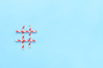 Hashtag from straws for drinks on a blue background. Concept sweets, drinks, online technology. Copy space, top view, flat lay.