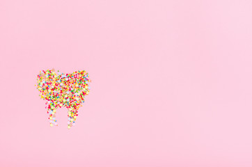 Tooth from confectionery dressing on a pink background. The concept of harmful sweets, dental health and smiles. Copy space, top view, flat lay.