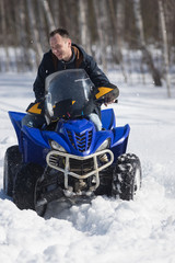 A man in warm jacket riding snowmobile in the winter forest