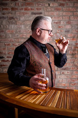 Man tasting whisky on a Bar in Front of a red stone wall