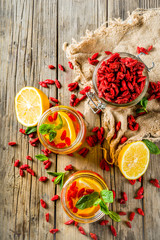 Homemade goji hot tea with mint and lemon slices, wooden rustic background copy space