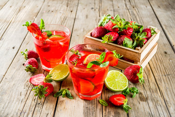 Homemade strawberry lemonade with lime and mint, rustic wooden background copy space