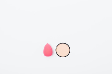Makeup sponge next to compact powder on white table, top view. Flat lay composition of beauty product and accessory, copy space.