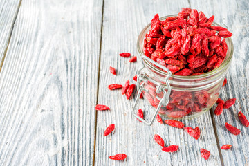 Dried goji berries in little jar, wooden background copy space