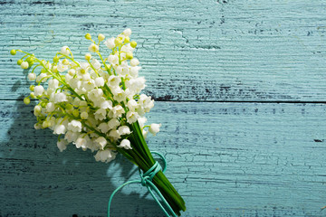 Lily of the valley flowers on cracked blue wood table background, directly above - obrazy, fototapety, plakaty