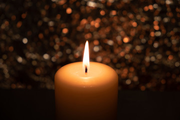 burning candle in the dark on a brilliant background