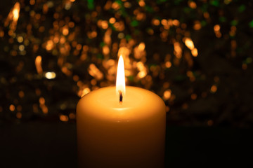 burning candle in the dark on a brilliant background