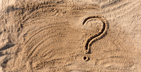 question marks written on beach sand close up, with copy space