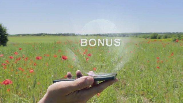 Hologram of Bonus on a smartphone. Person activates holographic image on the phone screen on the field with blooming poppies