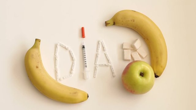 The word DIABETES or DIA from lancets for glucometer, insulin syringe and fresh bananas on white background.