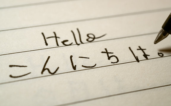 Beginner Japanese language learner writing Hello word in Japanese hiragana characters on a notebook