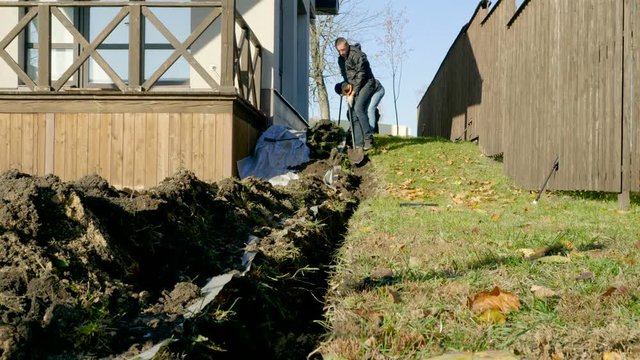 Two men digging a trench using shovels to make automatic watering of plants in the garden. 4K