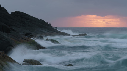 Fototapeta na wymiar Während des Sonnenaufgangs treffen Wellen auf die steinige Küste des Hat Head National Parks