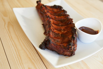 Grilled pork ribs with barbecue sauce on a white plate.