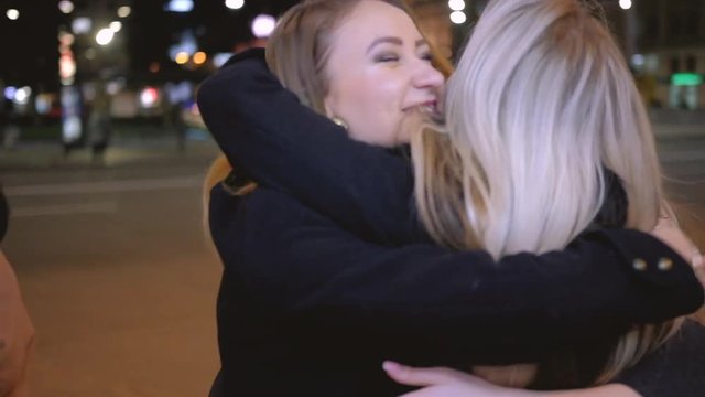 Girls night out. Special occasion. Female friends happy to meet for celebration. Street with blur city lights on background.