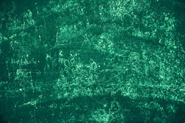 Vintage green background. Rough painted wall of emerald color. Imperfect plane of virid colored. Uneven old decorative toned backdrop of green tint. Texture of emerald hue. Ornamental stony surface.