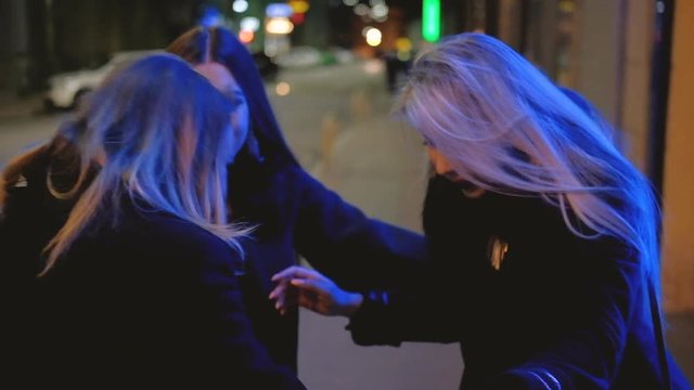 Ladies night out. Festive occasion. Female friends congratulating birthday girl, hugging on the street with blur city lights.