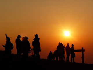 Silhouette of many tourists watching sunrise in viewpoint on mountain