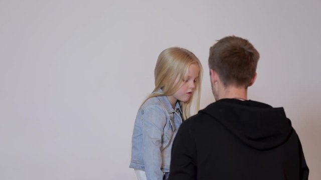 professional photographer talking to a cute little model girl at a photo shoot in a photo studio. the photographer explains to the child how to pose