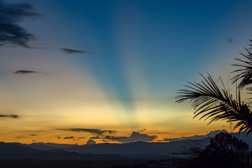 Multiple exposure of beams of light crossing the sky in an almost clear sunset over the central Andean mountains of Colombia.