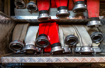 Rolled fire hoses, arranged in rows, in the glove compartment of the fire truck.
