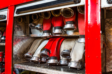 Rolled fire hoses, arranged in rows, in the glove compartment of the fire truck.