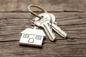 Keychain house with keys on old wooden boards.