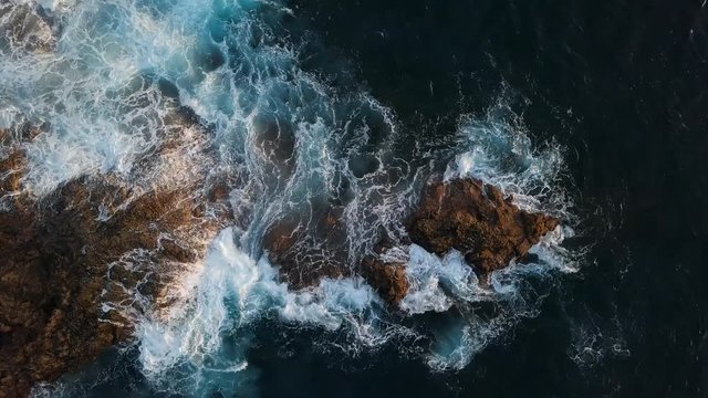 Top aerial view of ocean waves splash against rocks background, Tenerife, Canary islands, Spain.