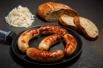 five tasty ruddy juicy sausages fried in large frying pan