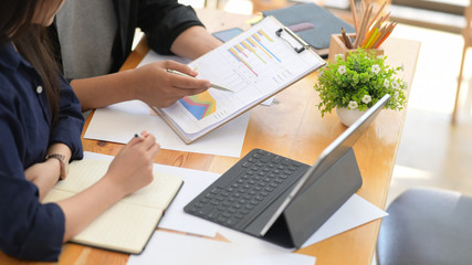 Businessman and businesswoman sitting at table working with data