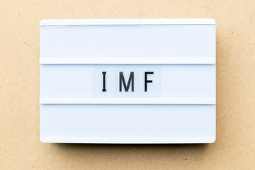 White lightbox with word IMF (Abbreviation of International Monetary Fund) on wood background